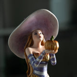 Closeup of witch in purple holding up a pumpkin