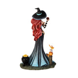 Figurine of witch holding apple, at her feet are pumpkins, fairy frog, cauldron of fruit. Shown from the back