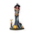 Figurine of witch holding apple, at her feet are pumpkins, fairy frog, cauldron of fruit