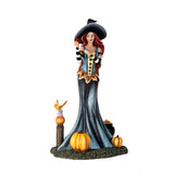 Figurine of witch holding apple, at her feet are pumpkins, fairy frog, cauldron of fruit