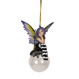 Fairy ornament with purple hair and striped pants sitting on a clear glass ball. Purple and yellow wings, gazing out