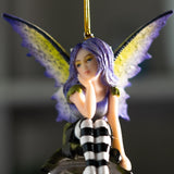 Fairy ornament with purple hair and striped pants sitting on a clear glass ball. Purple and yellow wings, gazing out