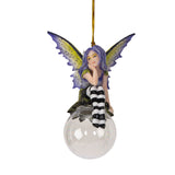 Fairy ornament with purple hair and striped pants sitting on a clear glass ball. Purple and yellow wings, gazing out
