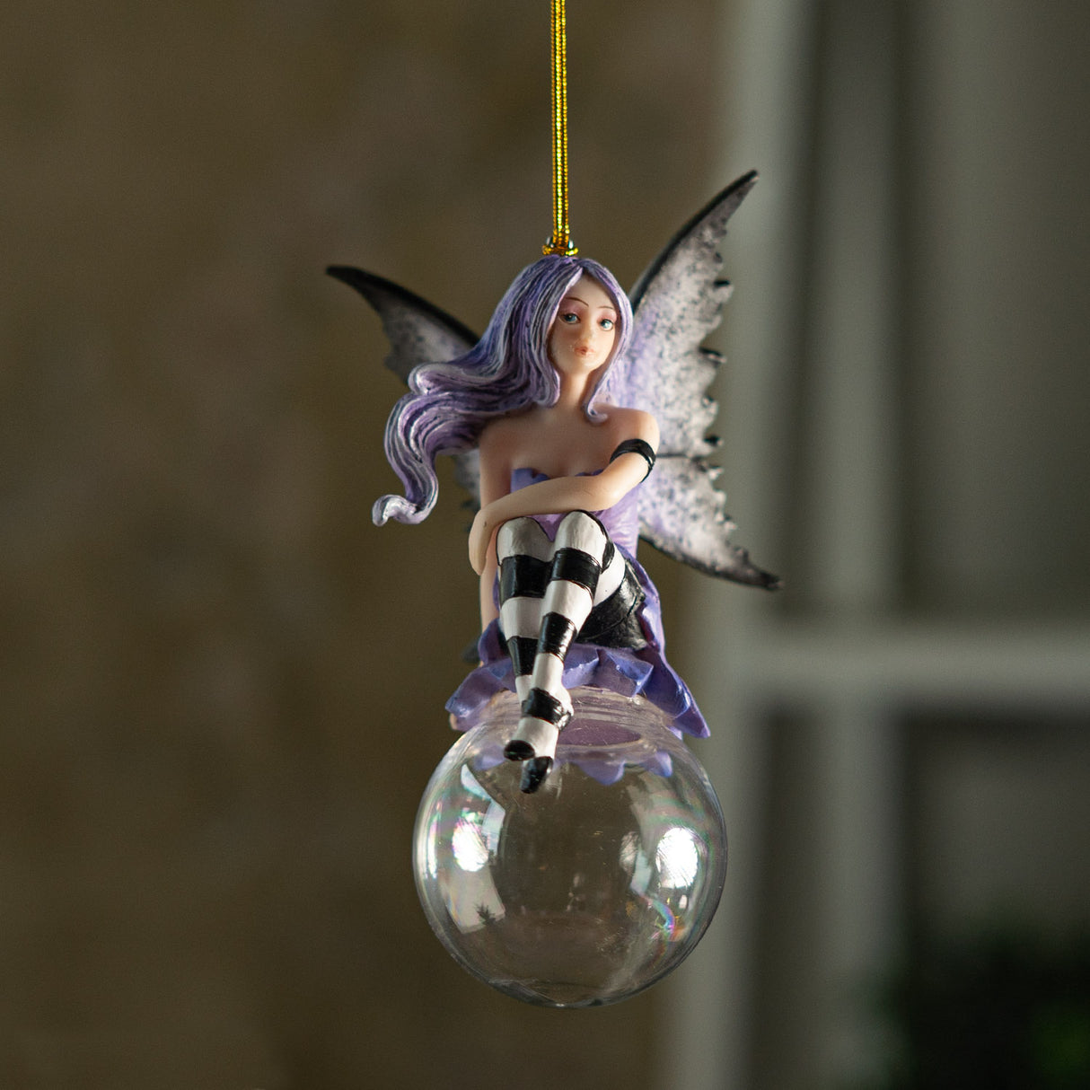 Fairy ornament with purple hair and dress, gray wings, black and white striped stockings, perched on glass bubble