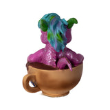 Colorful dragon figurine sitting inside a Cappuccino cup on a white background, shown from the back
