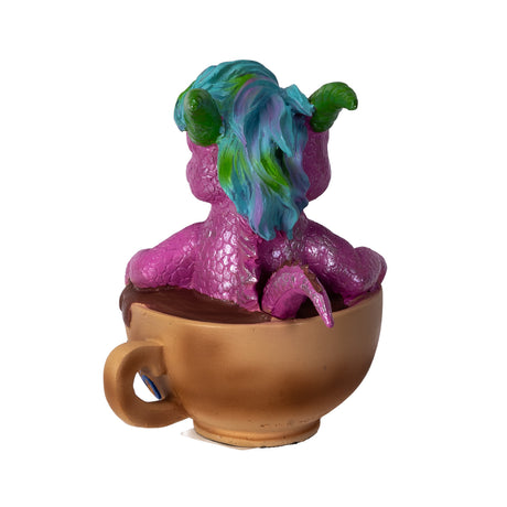 Colorful dragon figurine sitting inside a Cappuccino cup on a white background, shown from the back