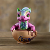 Colorful pink dragon figurine sitting inside a Cappuccino cup