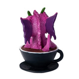 Pink dragon figurine inside a black coffee cup, shown from the back