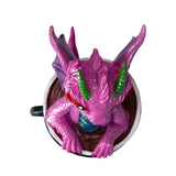Pink dragon figurine inside a black coffee cup, shown from above
