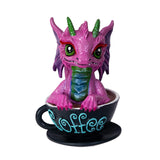 Pink dragon figurine inside a black coffee cup with 'Coffee' written on it against a white background
