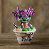 Pink/purple and green Dragon figurine sitting in an 'Iced Coffee' cup with a straw 