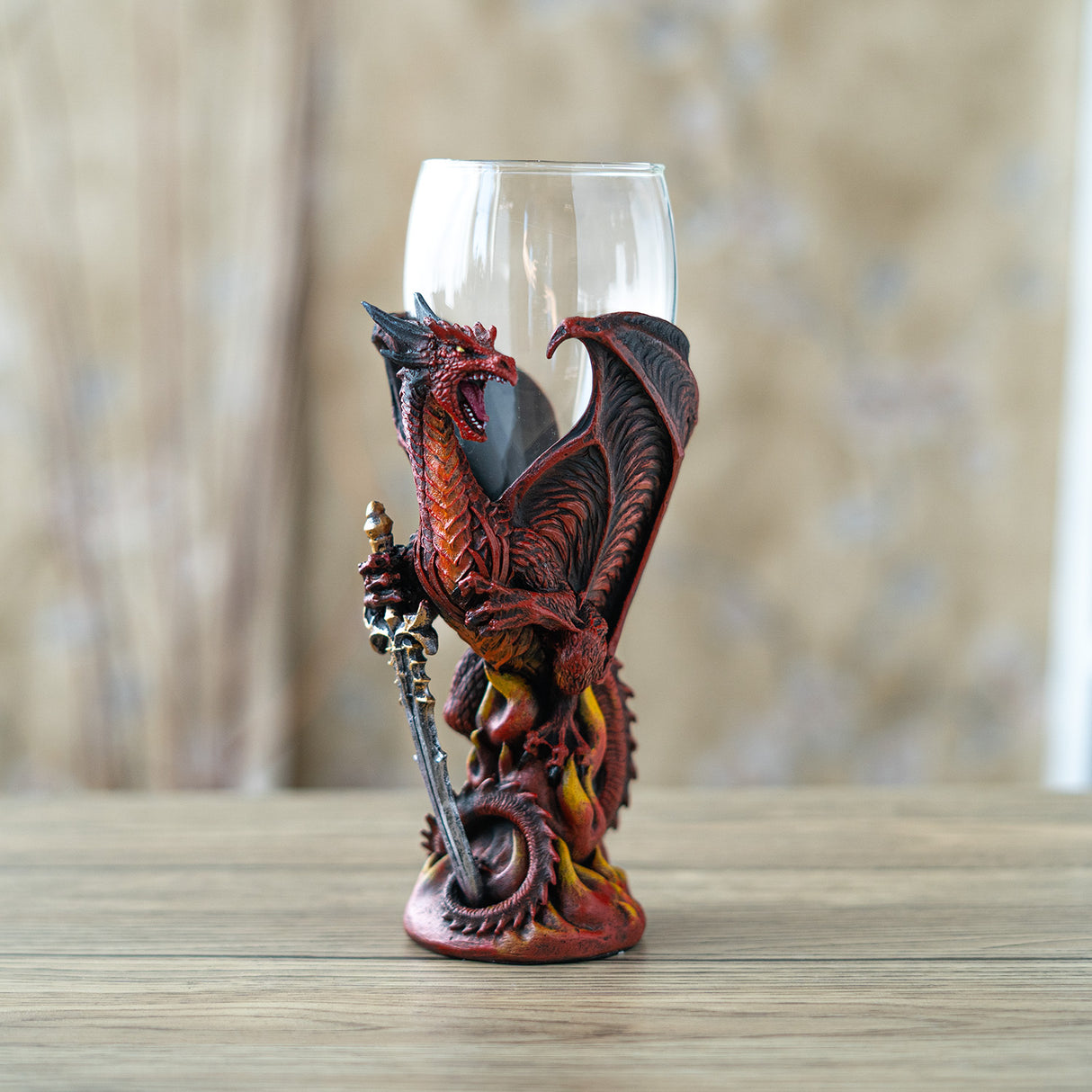 Glass-topped goblet with a red, orange and black dragon holding a sword 