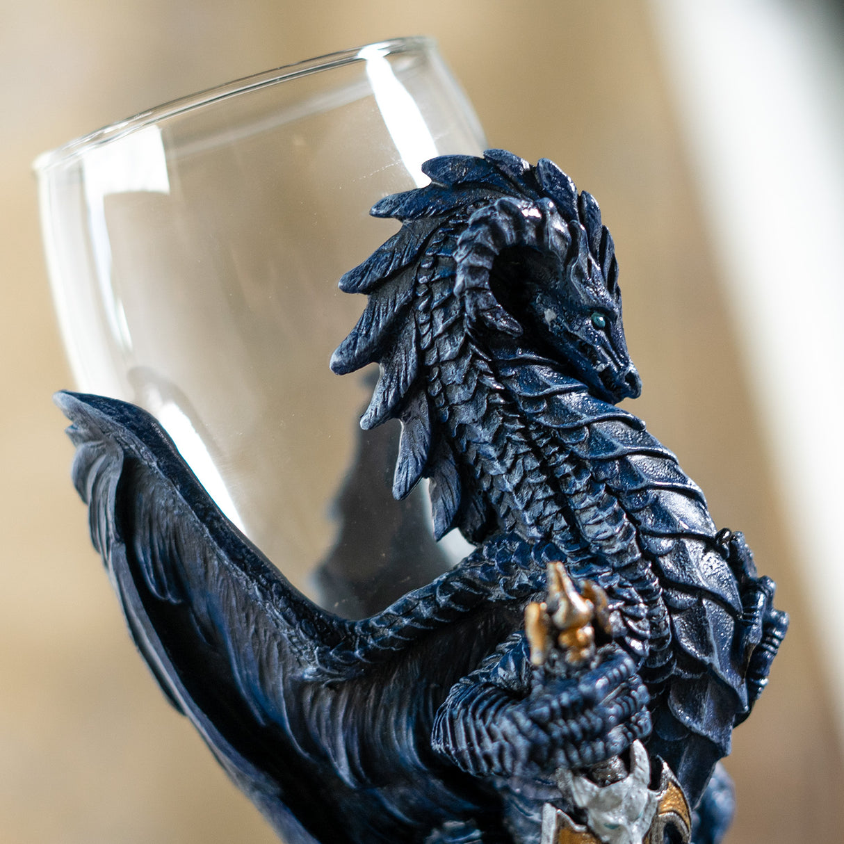 Closeup of blue dragon holding sword, glass goblet