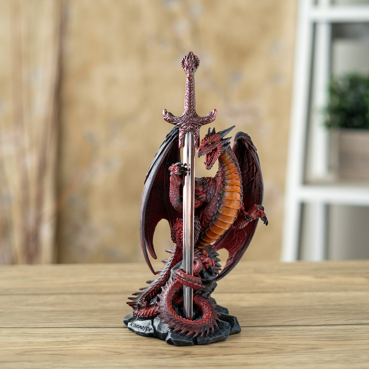 Dragon in shades of red, orange and black curled around a letter opener sword with red hilt