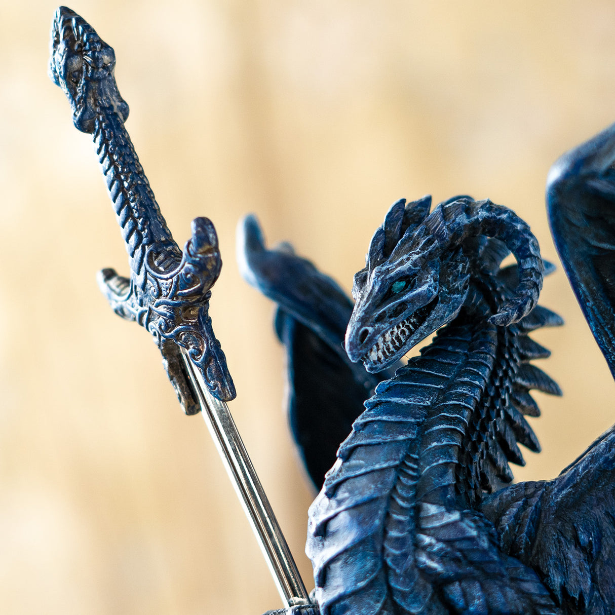 Closeup of blue dragon baring its teeth, holding sword letter opener