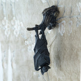 Decorative wall plaque of a black bat hanging upside down