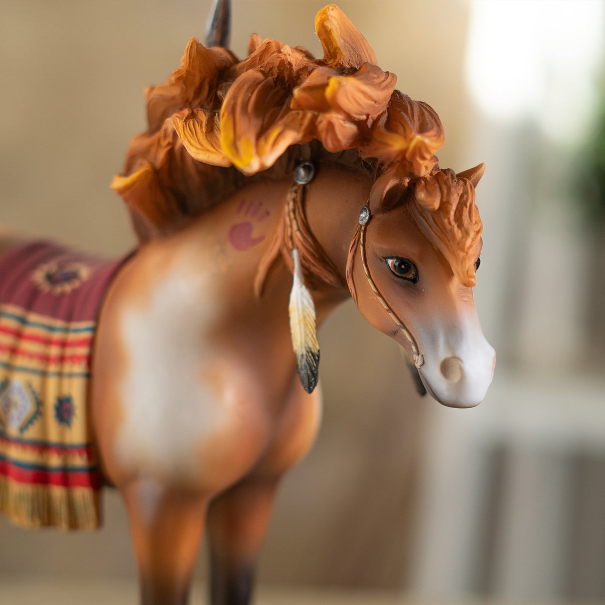 A decorative figurine of a horse standing on a black base with a gold plaque reading 'Medicine Horse.' The horse is a chestnut and white pinto with a multicolored saddle blanket and feather details in a Native American style