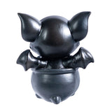 Small figurine of a black dragon imp, shown from the back, sitting in a cauldron
