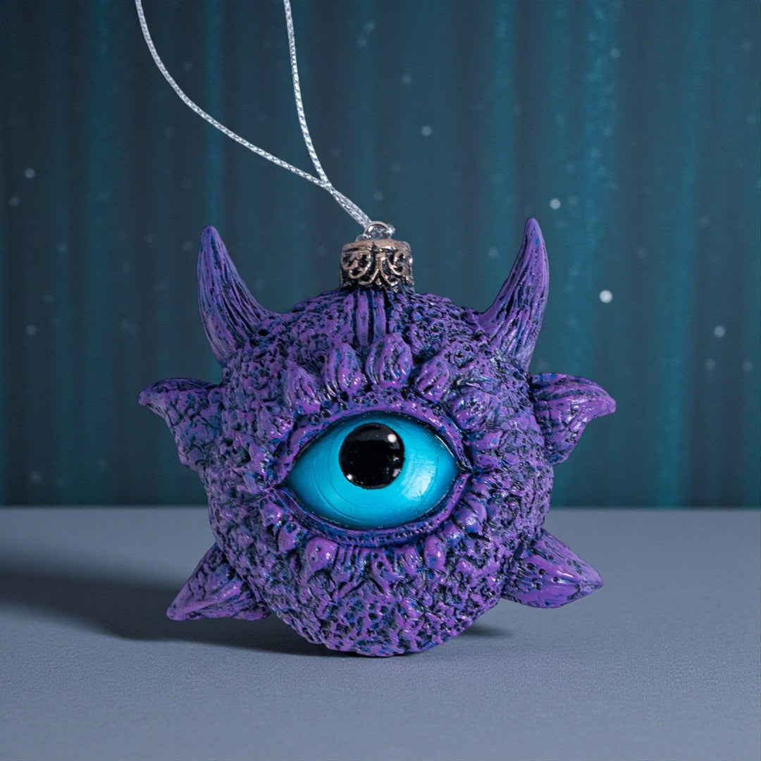 Ornament of a blue eye surrounded by purple scales and horns