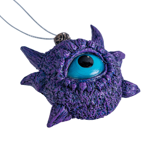 Ornament of a blue eye surrounded by purple scales and horns