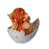 Small orange dragon figurine emerging from a cracked eggshell, shown from the back