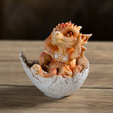 Small orange dragon figurine emerging from a cracked eggshell