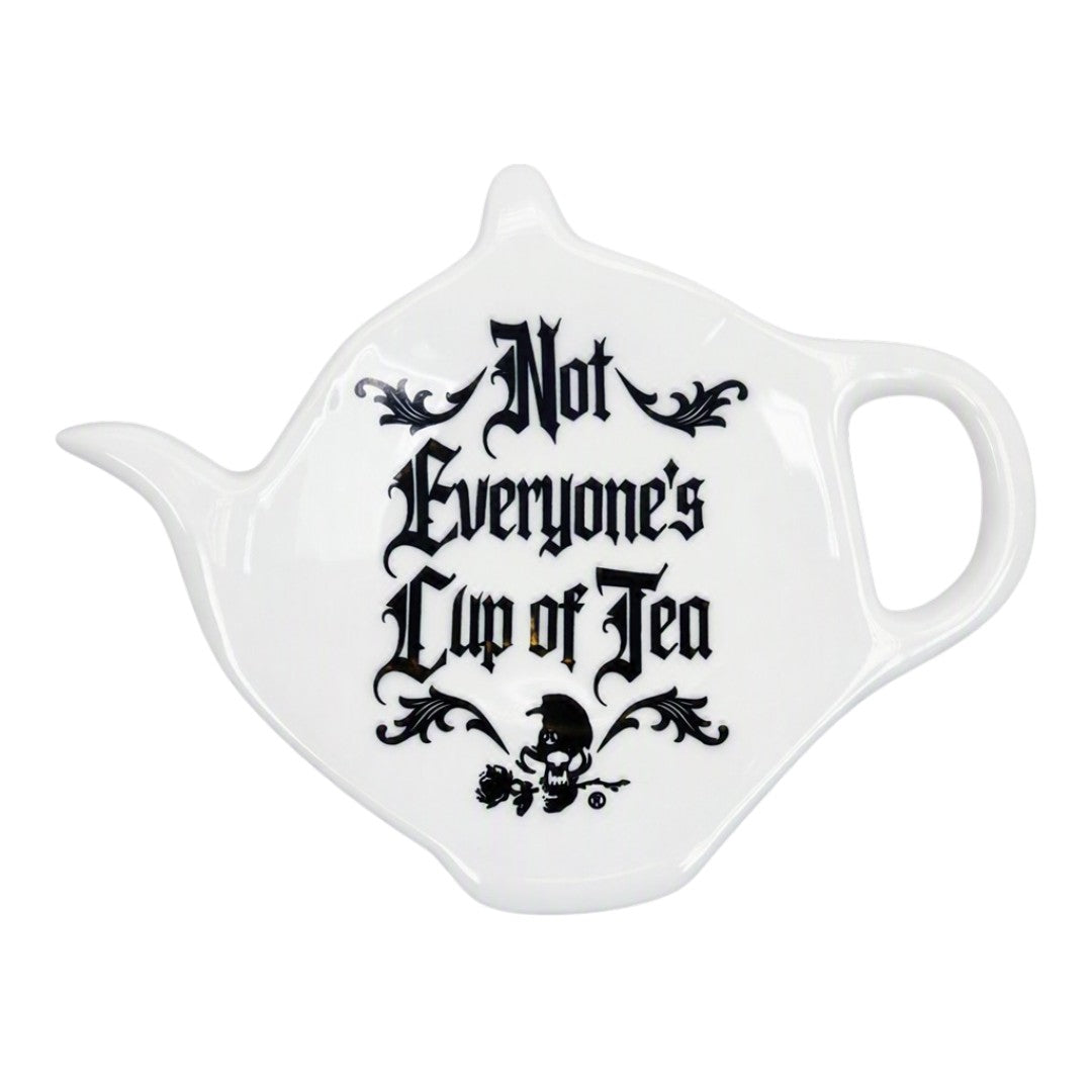A white ceramic teapot-shaped spoon rest with the phrase 'Not Everyone's Cup of Tea' printed in black gothic lettering and a small skull graphic, shown on a plain white background.