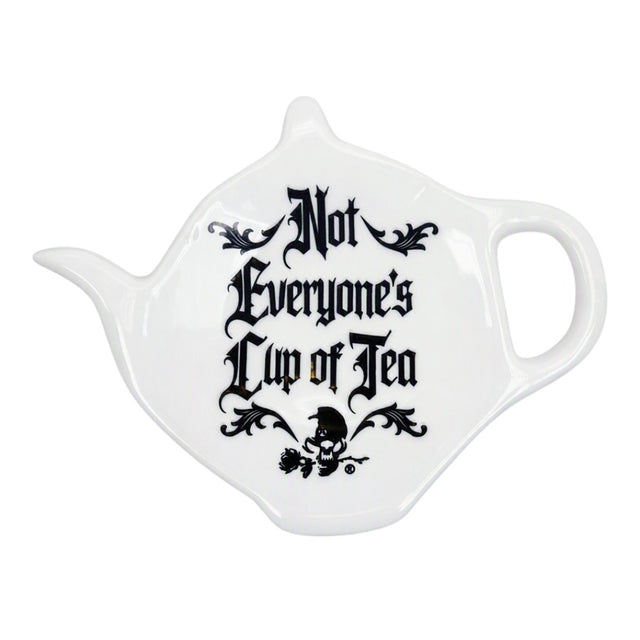 A white ceramic teapot-shaped spoon rest with the phrase 'Not Everyone's Cup of Tea' printed in black gothic lettering and a small skull graphic, shown on a plain white background.