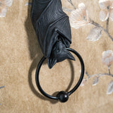 A black bat door knocker featuring a detailed bat sculpture hanging from a branch, with a circular ring at the bottom