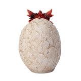 A small red dragon figurine sitting inside a cracked stone egg, shown from the back
