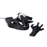 Dark gray faux-stone wall mounted lamp shaped like a dragon with an orb that glows, shown from the top