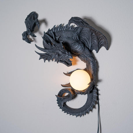 Dark gray faux-stone wall mounted lamp shaped like a dragon with an orb that glows