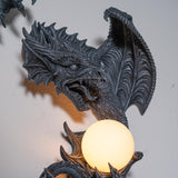 Dark gray faux-stone wall mounted lamp shaped like a dragon with an orb that glows