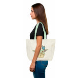 Tote bag with pale green handles and chibi Grogu with butterfly from The Mandalorian, worn by a woman