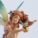 Figurine of a fairy leaning towards the butterfly on her hands. Red hair, green tipped wings, pink dress, sitting on a tree stump. Closeup of her face and the butterfly