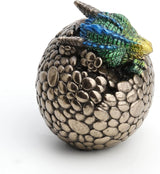 Green-blue-yellow baby dragon with blue eye hatching from metallic egg