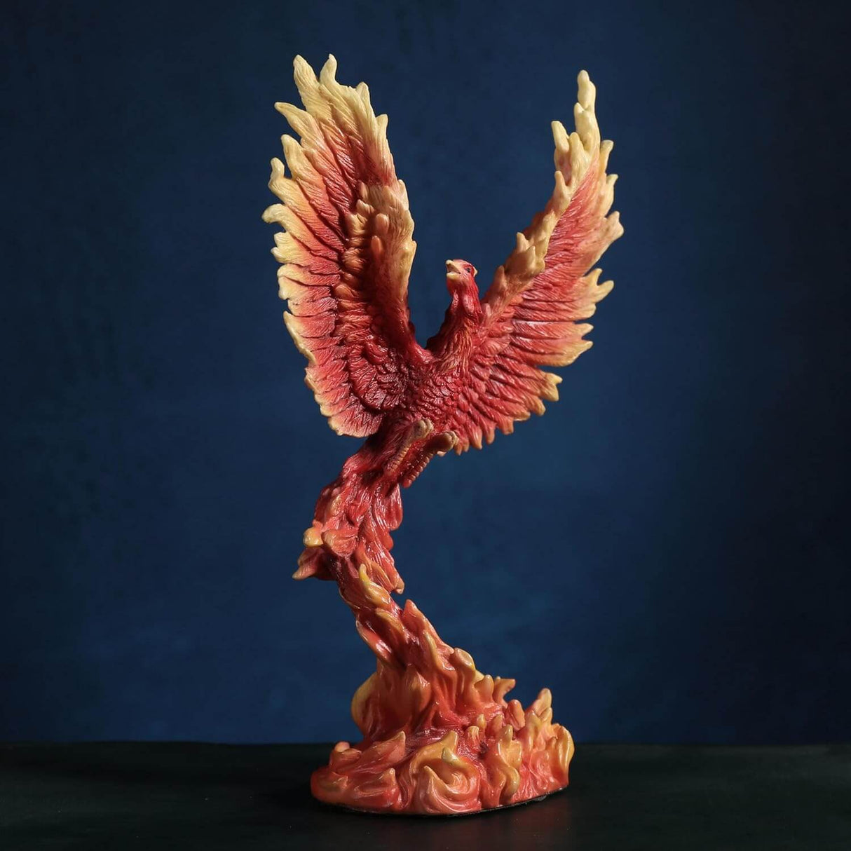 Figurine of a red, orange and yellow firebird rising from the flames