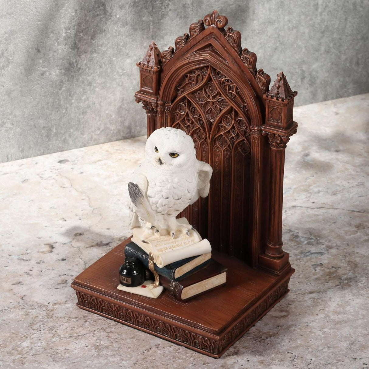 Snowy owl with golden eyes on bookstack holding quill, with faux-wood beyond