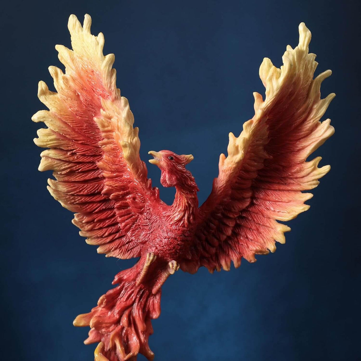 Figurine of a red, orange and yellow firebird rising from the flames