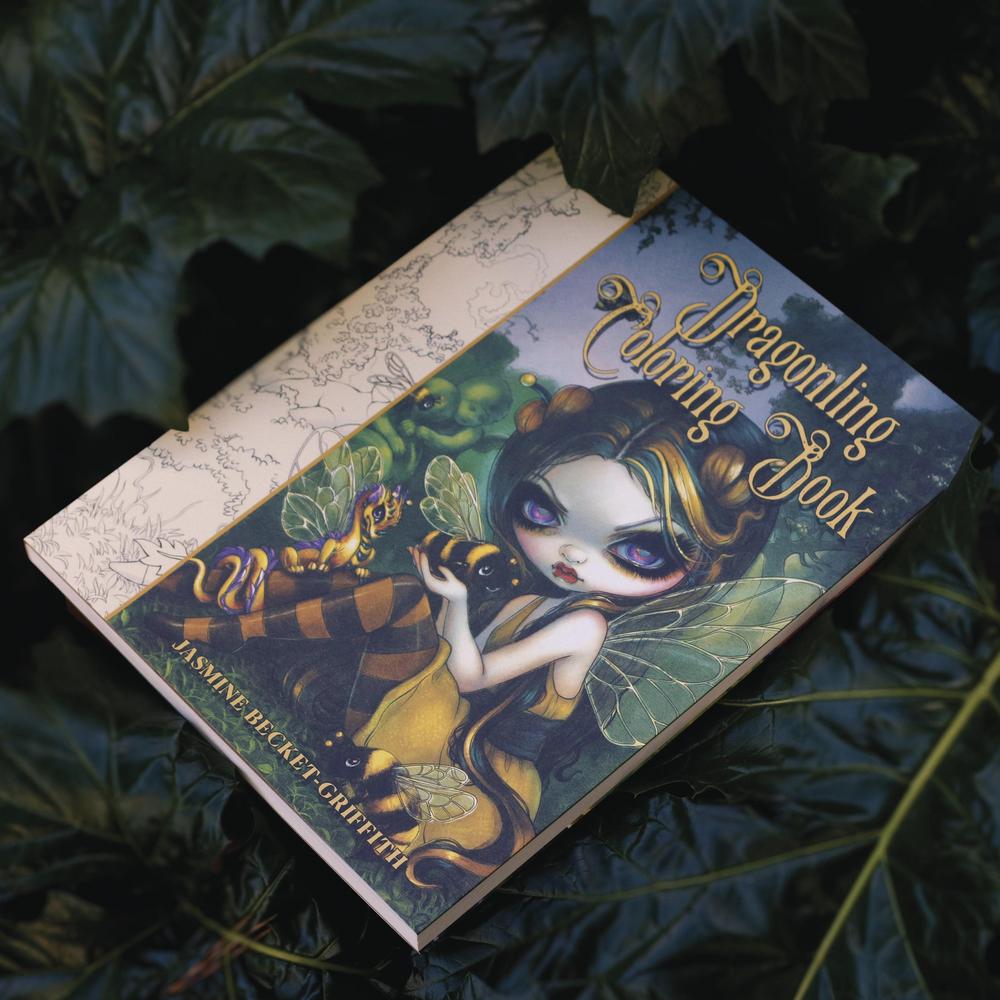 Dragonling Coloring Book by Jasmine Becket-Griffith on a dark leafy background
