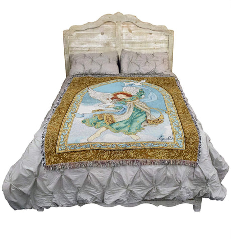 Tapestry blanket with an angel and doves surrounded by an elaborate floral border, shown on a bed