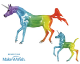 Two rainbow-colored unicorn figurines, mare and foal, on a white background with Make-A-Wish logo.
