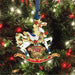 Brass rocking horse ornament with a box of toys, accented in holly and poinsettia, shown on a tree