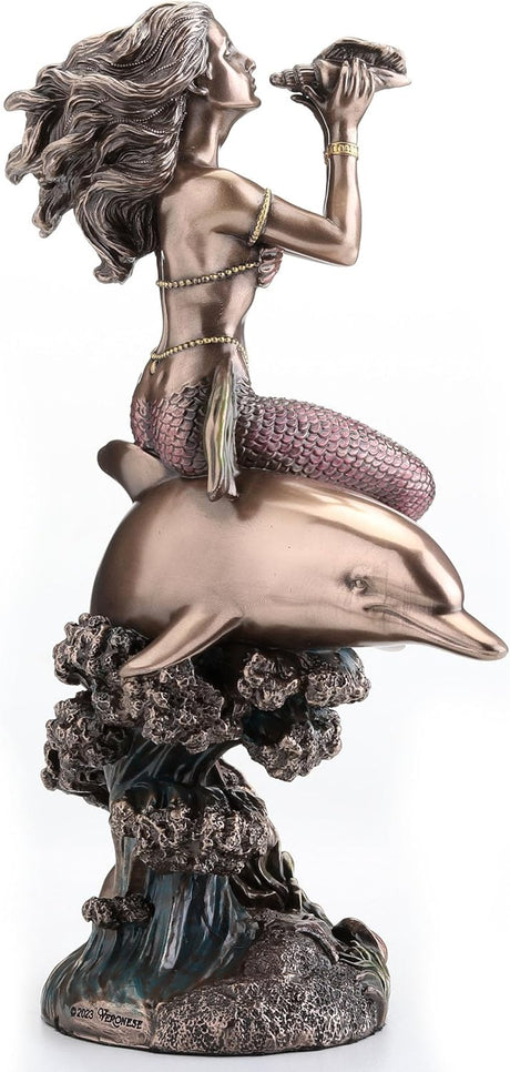 Bronze-hued mermaid on the back of a dolphin blowing into shell figurine