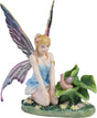 Blond fairy figurine with colorful wings sitting on flowers and grass with a snail on a leaf next to her