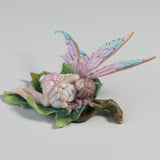 Fairy figurine with colorful wings, cuddling a bunny on a leaf
