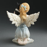 Angel figurine holding a small French Bulldog, shown from the back