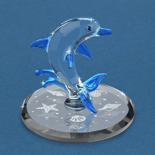 Glass figurine of a dolphin jumping out of the water in blue and clear with crystal eye, on mirrored base with white seashell deisgns