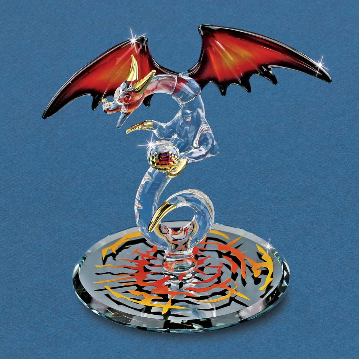 Glass dragon figurine with black and red wings, gold accents, holding crystal ball on a mirror base with fiery colored designs