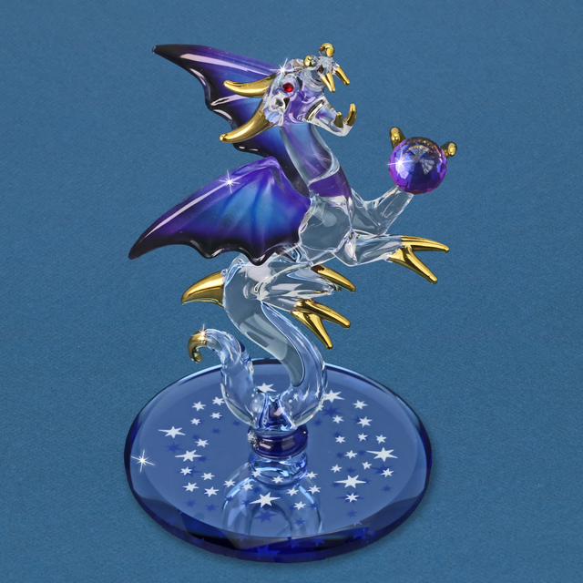 Glass dragon figurine with blue and black wings, gold accents, holding indigo ball on mirror base with white stars